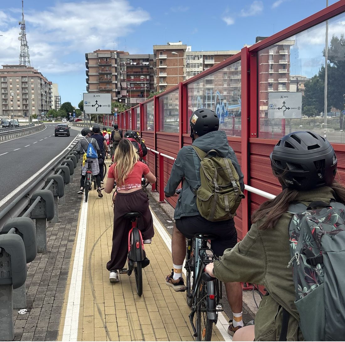 A group of people riding in a line along an urban cycle path in Bari